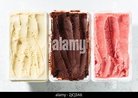 Vero gelato artigianale italiano in confezione: Cioccolato, fragole, vaniglia con frutti di bosco e un cucchiaio Foto Stock