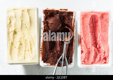 Vero gelato artigianale italiano in confezione: Cioccolato, fragole, vaniglia con frutti di bosco e un cucchiaio Foto Stock