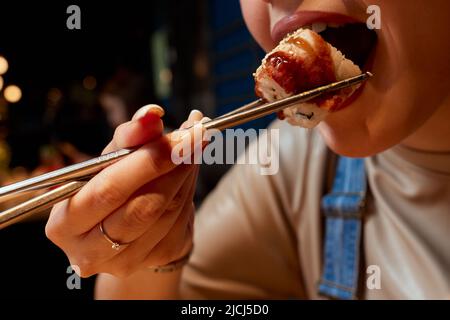 Giovane donna corto 20s indossare abiti casual tenere in mano makizushi sushi rotolo servito su piatto tradizionale cibo giapponese Foto Stock