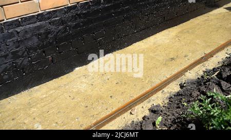 La sabbia è versata con acqua per stendere le lastre di pavimentazione. Il processo di posa di lastre di pavimentazione. Umidificazione della sabbia per pavimentazioni. Sabbia è versata da un tubo Foto Stock