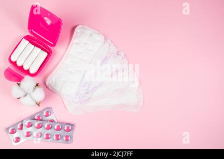 Set di prodotti per l'igiene femminile per mestruazioni. Tamponi sanitari, tamponi, pillole su sfondo rosa. Concetto di salute delle donne. Spazio di copia. Foto Stock