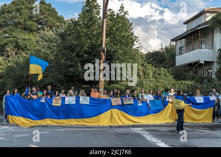 Sofia, Bulgaria, 13 giugno 2022: Le persone che detengono bandiera Ucraina gigante e manifesti a sostegno dell'Ucraina si trovano di fronte all'ambasciata russa Foto Stock
