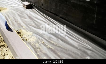 La base da una tela oleata per la posa di lastre di pavimentazione. Preparazione del basamento per la posa di lastre di pavimentazione. Il processo di preparazione della posa delle piastrelle o Foto Stock