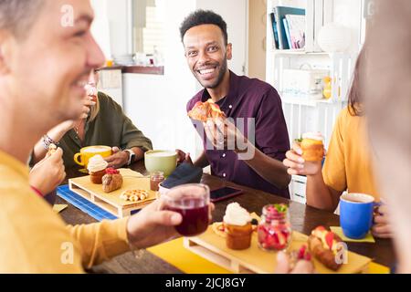 Persone che si divertono in caffetteria. Amici che prendono tempo di colazione bevendo succhi di caffè e mangiare torte. Stile di vita e concetto di comunità con uomini felici Foto Stock