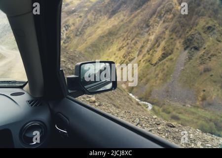Concetto di viaggio in auto. Specchietto laterale di un'auto nera vista dall'interno. Splendida vista sulle montagne naturali. Foto di alta qualità Foto Stock