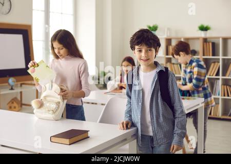 Bel ragazzo in primo piano mentre i compagni di classe si preparano per la lezione in classe Foto Stock