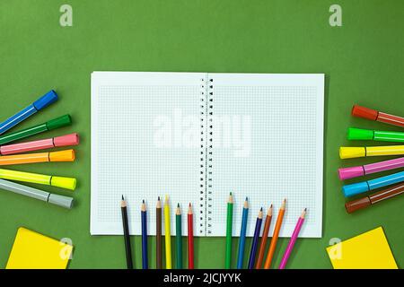 Pennarello, matite colorate e nota per il disegno. Cancelleria su sfondo verde. Concetto di ritorno a scuola, istruzione. Spazio di copia Foto Stock