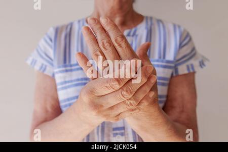 una donna anziana che soffre di dolore in mano sfrega il polso, primo piano Foto Stock