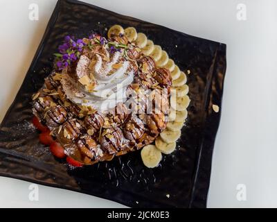 Waffle all'uovo di Hong Kong con fragola, banana e panna montata Foto Stock