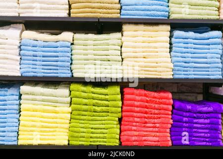 Tovaglioli multicolore su scaffale sul mercato, vendita tovaglioli di cotone, pila di tovaglioli di cotone colorati, uno scaffale nella fila di casa del mercato, primo piano selettivo messa a fuoco Foto Stock