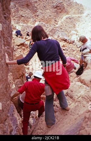 Turisti che si arrampicano sulle rocce visitando siti preistorici, Parco Nazionale Tassili N'Ajjer, Algeria, Nord Africa 1973 Foto Stock