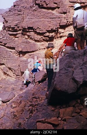 Turisti che si arrampicano sulle rocce visitando siti preistorici, Parco Nazionale Tassili N'Ajjer, Algeria, Nord Africa 1973 Foto Stock