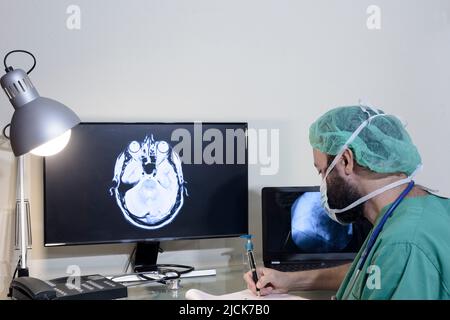 Nel laboratorio medico, il paziente viene sottoposto a una scansione RM o TC sotto la supervisione di un radiologo, nella sala di controllo, il medico osserva Foto Stock