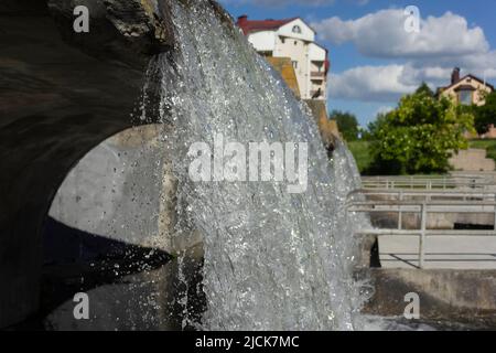 Una piccola cascata vicino alle case di una città europea. Scatto macro di una cascata Foto Stock