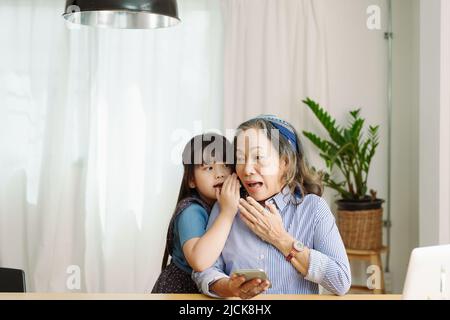 Ritratto asiatico, nonna e nipote fare il tempo libero con i bambini piccoli sussurrando segreti tra di loro Foto Stock