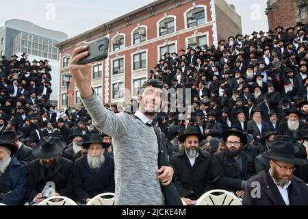 Al convegno annuale degli emissari di Chabad un giovane uomo israeliano prende un selfie di fronte a centinaia di rabbini riuniti per una foto di gruppo. Foto Stock