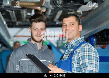 due meccanici che lavorano sotto un'auto Foto Stock