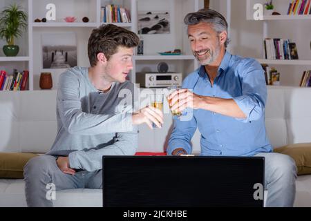 Padre e figlio tostano con i loro bicchieri di birra Foto Stock