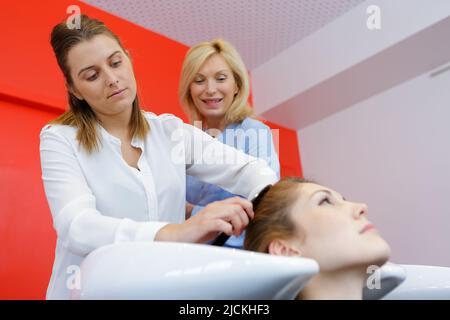 Insegnante aiuta gli studenti a formazione per diventare parrucchieri Foto Stock