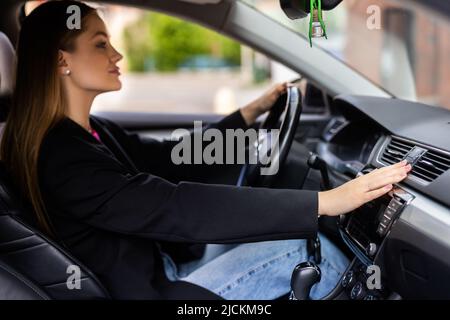 Donna che preme il pulsante di emergenza sul cruscotto dell'auto Foto Stock