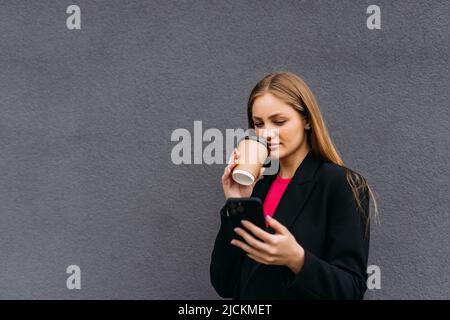 Bella donna che va a lavorare con caffè a piedi vicino Office Building. Ritratto di successo donna d'affari che tiene la tazza di bevanda calda. Foto Stock