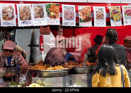 Un cuoco che serve cibo thailandese in un fast food al Magic of Thailand Festival al Basingstoke War Memorial Park. Giugno 12th 2022. Inghilterra Foto Stock