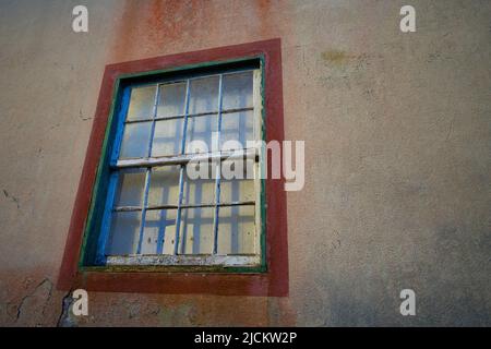 vecchia finestra in legno antico cornice intorno finestra in cemento parete esterna della casa urbana bianco telaio vetro con peeling vernice tenda tirata chiuso Foto Stock