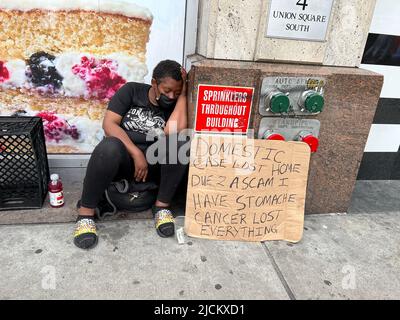 La donna senza tetto che è anche ammalata raggiunge per aiuto su 14th Street a New York City. Foto Stock