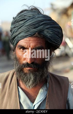 Il proprietario del negozio afghano locale fissa profondamente nella macchina fotografica a Kajaki, provincia di Helmond, Afghanistan. Foto Stock