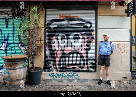 Uomo anziano vicino ad Angry man Street art su blinds del Faro Restaurant a Kreuzberg, Berlino, Germania Foto Stock