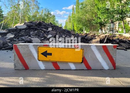 La strada è bloccata con blocchi di cemento a causa di riparazioni con un segno di deviazione sulla sinistra. Foto Stock