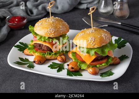 Hamburger fatti in casa a forma di tartaruga con formaggio toast, lattuga e pomodoro su un piatto bianco. Fast food per bambini Foto Stock