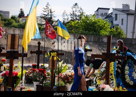 Lviv, Ucraina. 24th maggio 2022. Una donna che passa le tombe in un memoriale a Lviv. I pesanti combattimenti continuano nell'est dell'Ucraina, con luoghi chiave sotto intenso bombardamento da parte delle forze russe. La Russia ha compiuto progressi lenti ma significativi a est, e ora controlla oltre il 90% della regione di Luhansk. Mentre la morte continua ad aumentare, la regione occidentale dell'Ucraina come la città di Lviv ha tenuto memoriali per il diminuito quasi ogni giorno dall'inizio della guerra, e non c'è fine in un breve periodo di tempo. (Credit Image: © Dominic Chiu/SOPA Images via ZUMA Press Wire) Foto Stock