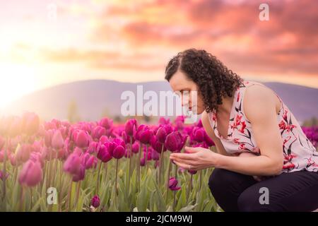 Caucasica Adulto Donna che odora freschi fiori di tulipano in un campo. Foto Stock