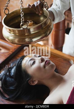 Una donna riceve un trattamento ayurvedico Shirodhara. Foto Stock