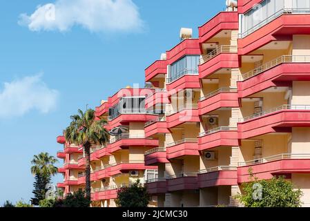 Una fila di edifici residenziali della Turchia meridionale con balconi contro il cielo e il verde. Foto Stock