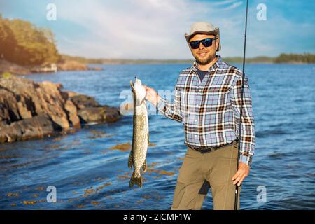 pescatore sorridente con pesce luccio pescato in mano Foto Stock