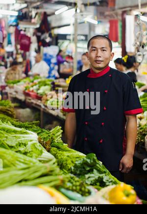 Asian maschio Sous Chef shopping al mercato vegetale a Siem Reap, Cambogia. Il tour del mercato e la lezione di cucina sono attività per gli ospiti. Foto Stock