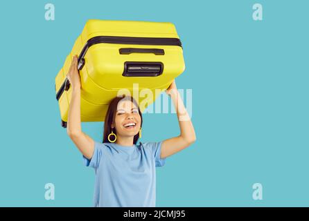 Una donna allegra che sta andando in vacanza è portare la sua valigia gialla e ridere Foto Stock