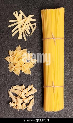 Spaghetti con vari tipi e forme di pasta italiana su fondo nero. Vista dall'alto. Foto Stock
