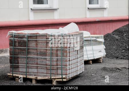 lastre per pavimentazione in calcestruzzo impilate su pallet. Ricostruzione delle infrastrutture urbane. Foto Stock