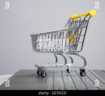 Shopping su Internet. Computer portatile, piccolo carrello e carte di  credito sul tavolo al coperto, guardaroba Foto stock - Alamy