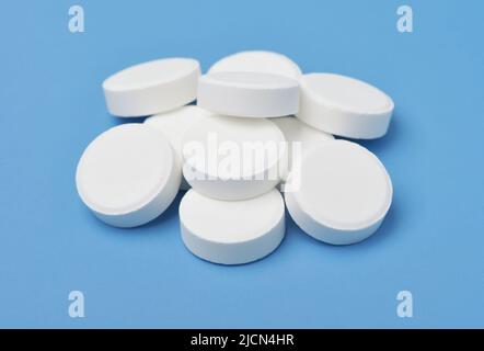 Gruppo di pillole mediche bianche isolato su sfondo blu Foto Stock
