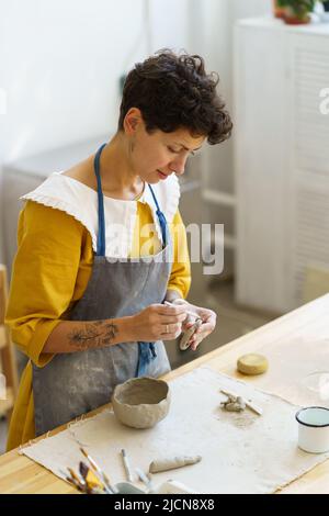 Vasaio giovane master stampaggio artigianale tazza ceramica pentola utilizzando strumenti professionali per la formazione di argilla umida Foto Stock