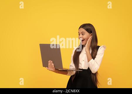 felice capretto in studio uniforme della scuola sul laptop, formazione in linea Foto Stock