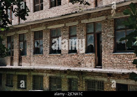 Il muro di un vecchio edificio abbandonato in mattoni con finestre rotte. Foto Stock