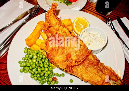 Pesce e patatine servite con piselli e salsa tartara Foto Stock