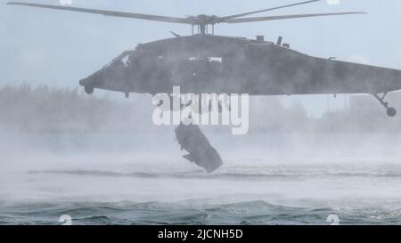 Berette verdi con 2nd battaglione, 10th Special Forces Group (Airborne), gettò una barca gonfiabile militare da un elicottero UH-60 Black Hawk vicino Key West, Florida, 3 maggio 2022. Helocast, o free-drop da un elicottero, è un mezzo per inserire i nuotatori/subacquei da combattimento e le imbarcazioni a mobilità marittima in un ambiente marino. (STATI UNITI Foto dell'esercito dello staff Sgt. Antonio Bryant) Foto Stock