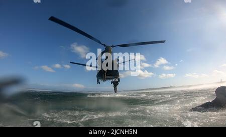 Soldati delle forze speciali con 2nd battaglione, 10th Special Forces Group (Airborne), gettati nel Golfo del Messico da un elicottero CH-47 Chinook vicino Key West, Florida, 3 maggio 2022. Helocast, o free-drop da un elicottero, è un mezzo per inserire i nuotatori/subacquei da combattimento e le imbarcazioni a mobilità marittima in un ambiente marino. (Foto DOD) Foto Stock