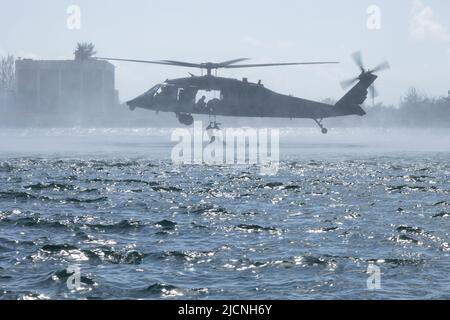 Un berretto verde assegnato a 2nd battaglione, 10th Special Forces Group (Airborne), sale una scala fissata a un elicottero UH-60 Black Hawk vicino alla Special Forces Underwater Operations School in Fleming Key, Florida, 3 maggio 2022. L'Helocasting è stato condotto per familiarizzare il personale delle forze operative speciali con le tecniche di inserimento ed estrazione in un ambiente di acqua spesso utilizzato in aree semi- o non permissive per rimanere clandestino. (STATI UNITI Foto dell'esercito dello staff Sgt. Antonio Bryant) Foto Stock